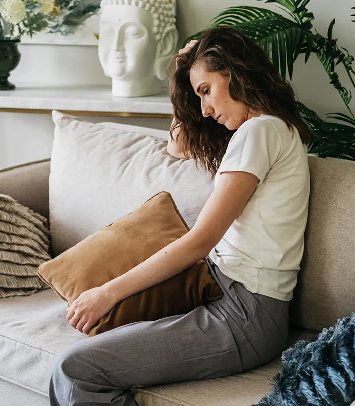sad-woman-sits-sofa-home-hugging-pillow