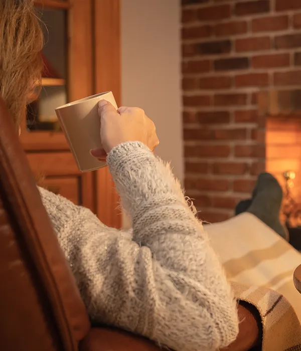 woman-having-cup-coffee-front-fire-fireplace-winter
